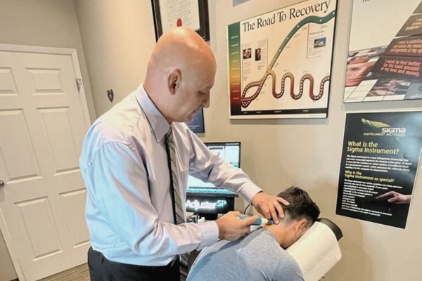 a chiropractor using a Sigma machine to work on a patients neck